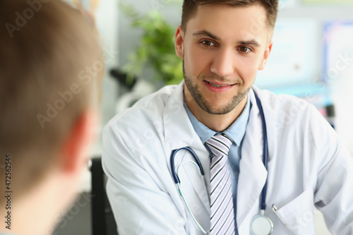 Young male doctor listens to a patient, close-up face