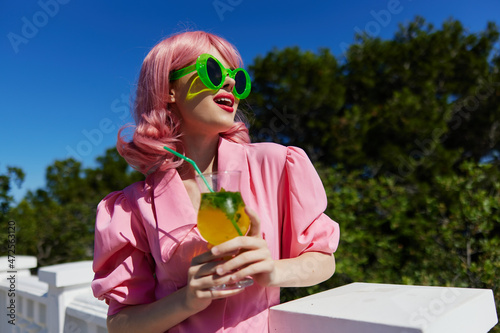 portrait of beautiful woman in green sunglasses with cocktail in summer outdoors unaltered
