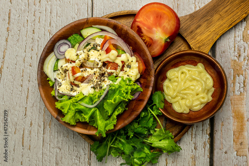 Homemade salad with dressing,cucumber, tomatoes,lettuce,shallot and cream cheese. Rustic style. Selective Focus. Top view. Copy space. No.01