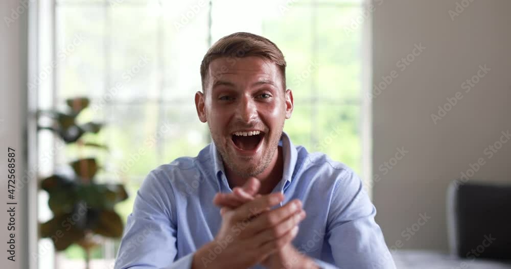 Portrait close up video shot of Caucasian young handsome confident glad joyful bearded unshaven male businessman in blue casual shirt look at camera smiling laughing happy show thumb up clap hands.