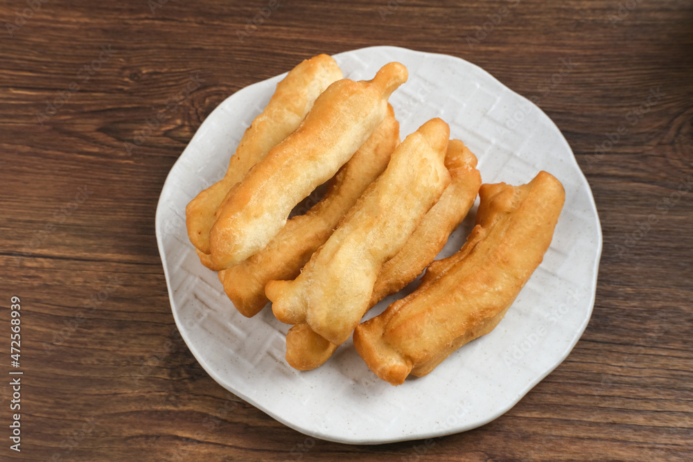 Cakwe or Cakue or Youtiao is traditional Chinese snack, long golden-brown deep-fried strip of dough and very popular in China and Asia. Selective focus image, copy space.
