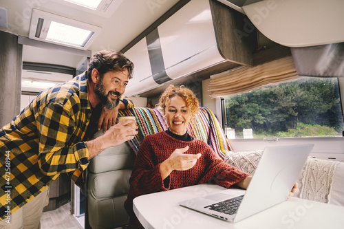 Foto Adult couple enjoy work together using laptop computer sitting inside camper rv vehicle