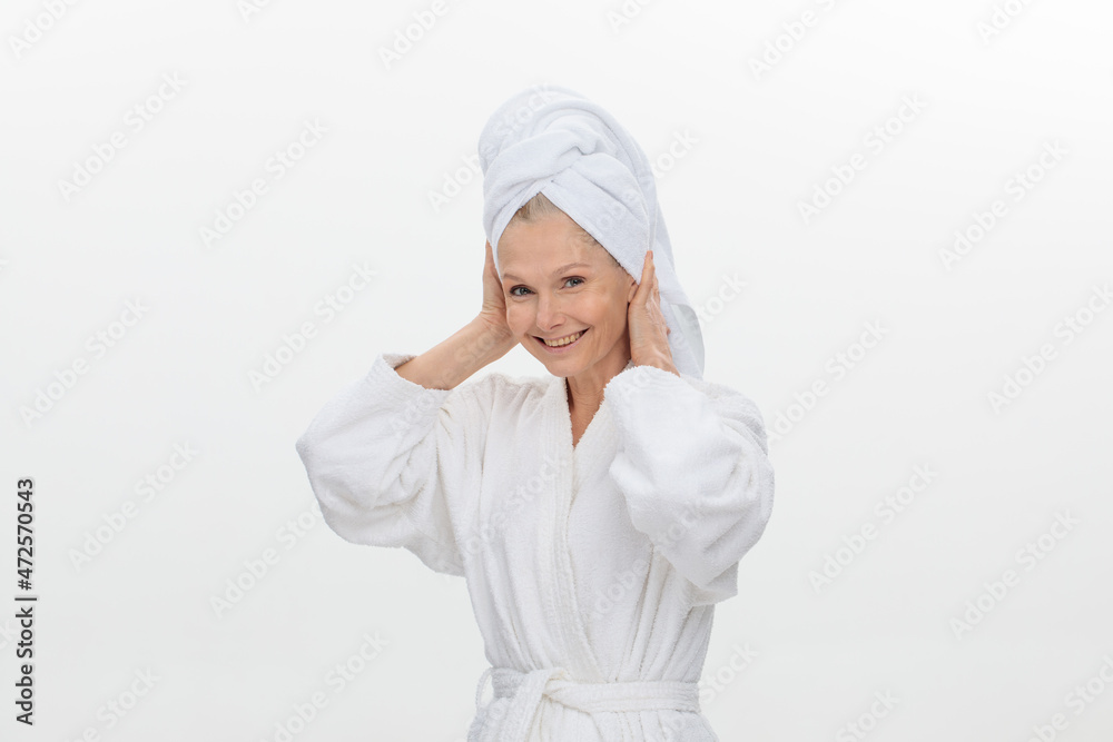 Image of joyful elderly adult woman wearing bathrobe and towel over her head smiling over white background Image of joyful elderly adult woman wearing bathrobe and towel over her head smiling over white background