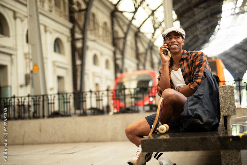 Happy young man waiting for the train. African man waiting in a subway. Man talking to the phone Happy young man waiting for the train. African man waiting in a subway. Man talking to the phone