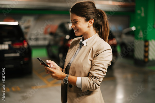 Businesswoman in suit unlocking car on parking. Beautiful woman talking to the phone..