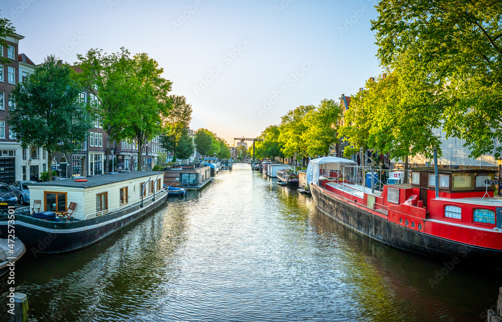 Schöner Sonnenuntergang über Amsterdam Stadt Landschaft in Niederlande mit Blumen und Fluss an der Brücke im Sommer. Natur Haus Boot Architektur Gracht