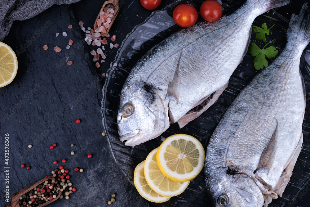 Raw dorado with spices ready to cook on a wooden background.