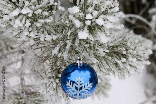Blue glass ball among the snow-covered pine branches. Festive decoration. New Year. 