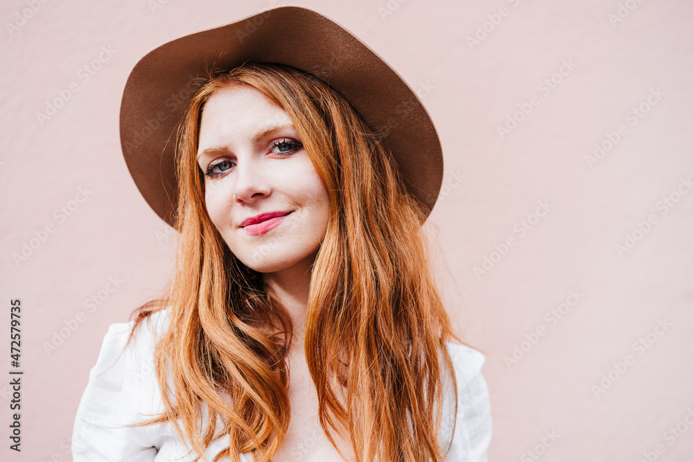 Beautiful woman wearing hat in front of pink wall Beautiful woman wearing hat in front of pink wall