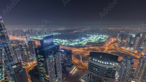 Aerial skyline with Golf Club, hotels and residential areas far away in desert in Dubai night timelapse, UAE, top view