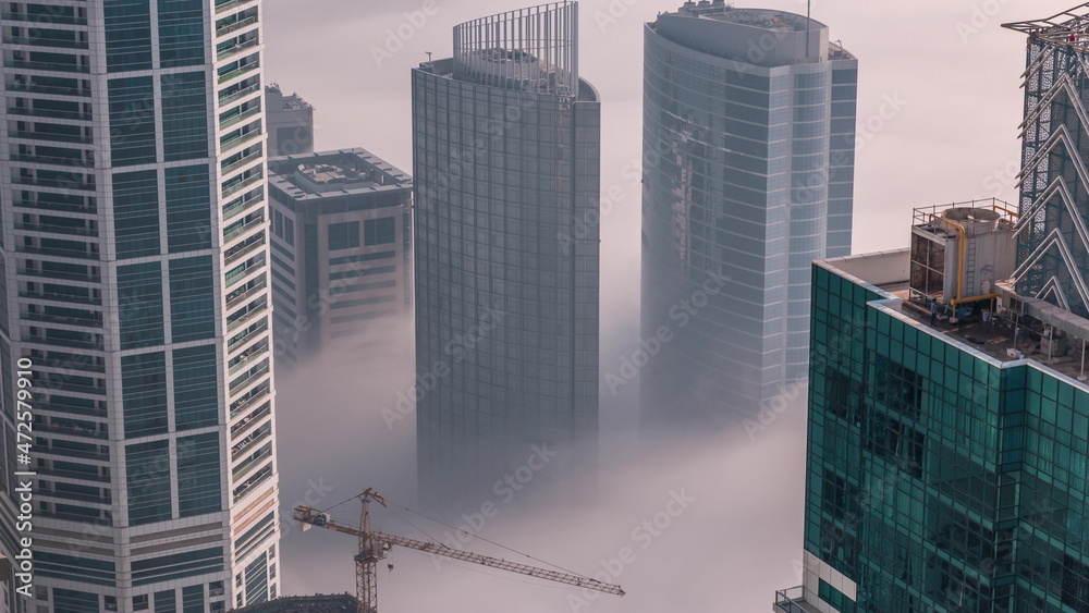 Fototapeta premium Rare early morning winter fog above the Dubai Marina skyline and skyscrapers rooftops aerial timelapse.