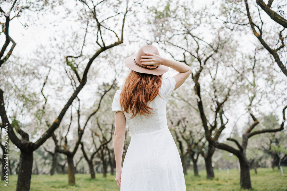 Redhead woman wearing hat standing in park Redhead woman wearing hat standing in park