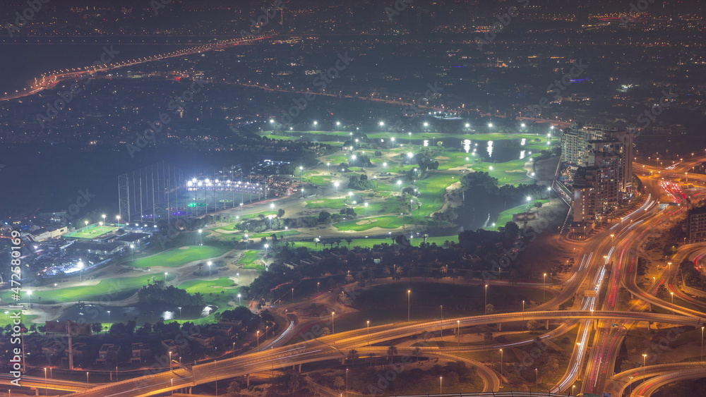 Aerial view to Golf course with green lawn and lakes, villas and houses behind it night timelapse.