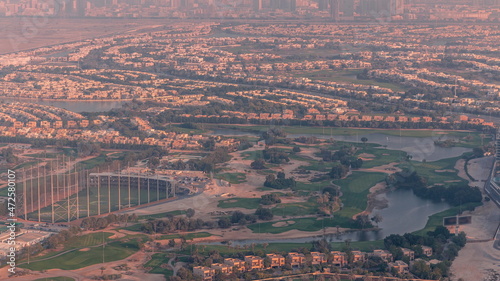 Aerial view to Golf course with green lawn and lakes, villas and houses behind it timelapse.