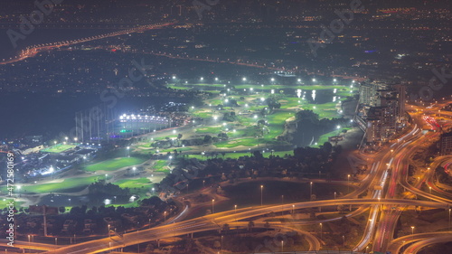 Aerial view to Golf course with green lawn and lakes  villas and houses behind it night timelapse.