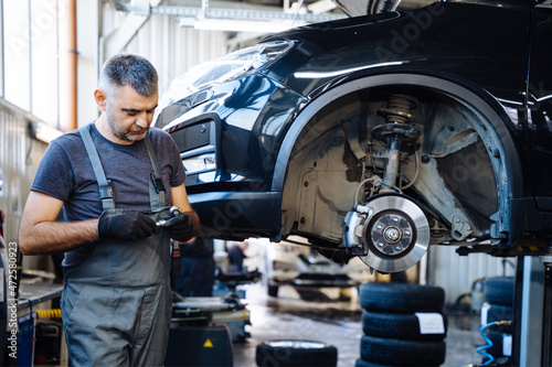?ar service, repair, maintenance concept. Mechanic in black gloves at work in his garage.