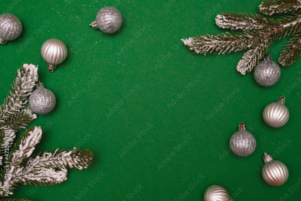 Obraz premium Christmas or New Year silver colored baubles, fir branches over green background. Greeting card. Minimal concept, copy space