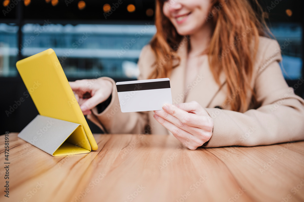 Smiling young woman using digital tablet while making payment through credit card at coffee shop Smiling young woman using digital tablet while making payment through credit card at coffee shop