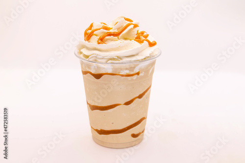Caramel flavoured frappe served in a plastic cup with whipped cream and dressing. photo