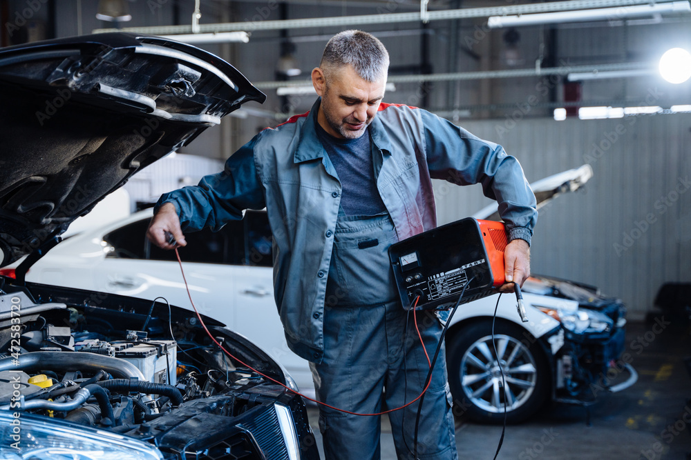 Auto service, repair, maintenance concept. Electrician mechanic technician working on a garage.