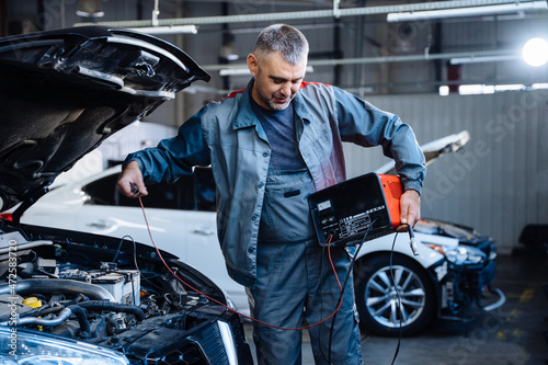 Auto service, repair, maintenance concept. Electrician mechanic technician working on a garage.