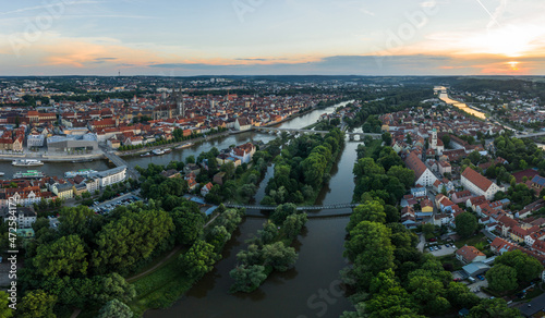 Panorama der Stadt Regensburg in Bayern mit dem Fluss Donau dem beleuchtetem Dom und der steinernen Brücke im Sommer zur blauen Stunde im Zwielicht, Deutschland