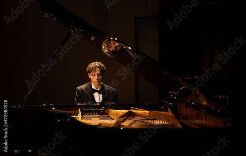 Foto Young 20s aspiring musician playing grand piano on a stage of a huge concert hal