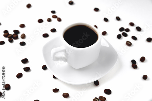 white cup of coffee on a white saucer on a white background isolate, close-up, top view, coffee beans lie on the background
