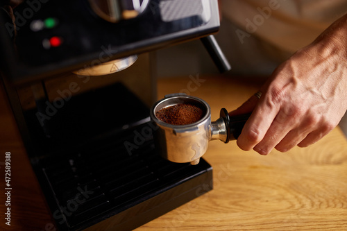 Female hands holding portafilter and making fresh aromatic coffee at home using a modern coffee maker  Male barista hand making espresso from ground coffee maker at modern cafe.