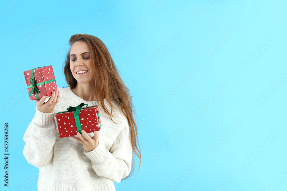 Attractive woman holds gift boxes on blue background Attractive woman holds gift boxes on blue background