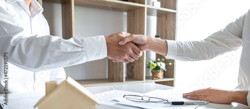 Real estate agent and customers shaking hands together celebrating finished contract after signing about home insurance and investment loan, handshake and successful deal