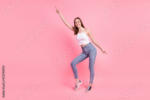 Full body photo of young cheerful girl indicate fingers empty space modern clothes isolated over pink color background