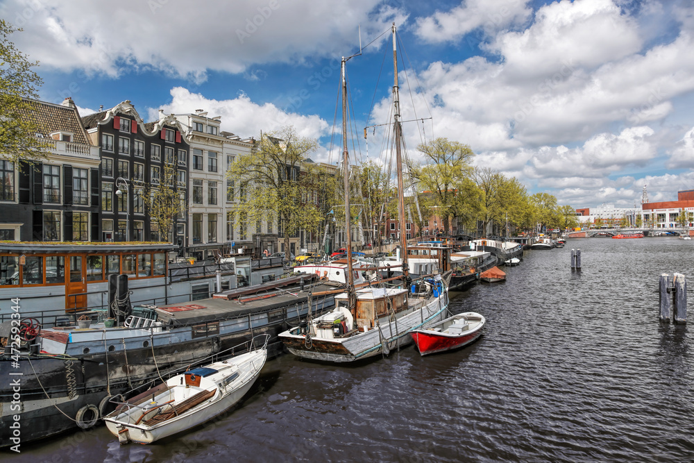 Amsterdam city with tourist boats on canal during springtime in Netherlands.