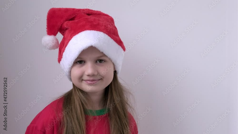 Portrait of smiling happy little girl in Christmas Santa hat on white background. New Year celebration, xmas new year advert promo. Cute child looking at camera. Copy space for text. Portrait of smiling happy little girl in Christmas Santa hat on white background. New Year celebration, xmas new year advert promo. Cute child looking at camera. Copy space for text.