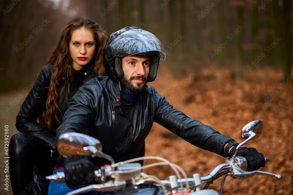 Obraz premium Couple of motorcyclists with a chopper in the woods in the fall.