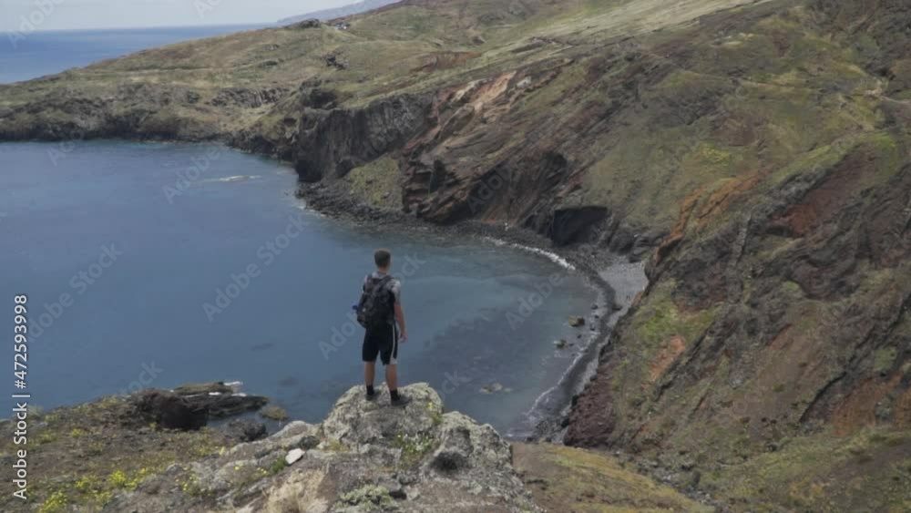 Man stands on rock overlooking beautiful small bay near Ponta de São Lourenço Man stands on rock overlooking beautiful small bay near Ponta de São Lourenço