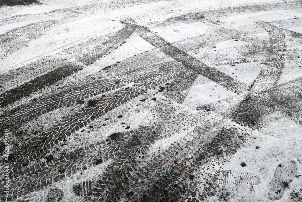 Fototapeta premium Snow on asphalt road with car imprints.