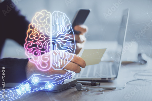 Double exposure of man's hand holding and using a digital device and brain hologram drawing. Data concept.
