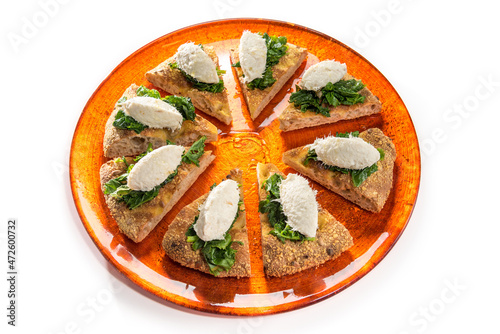 Venetian creamed cod quenelle with spinach on slices of wholemeal focaccia bread, on orange plate isolated on white