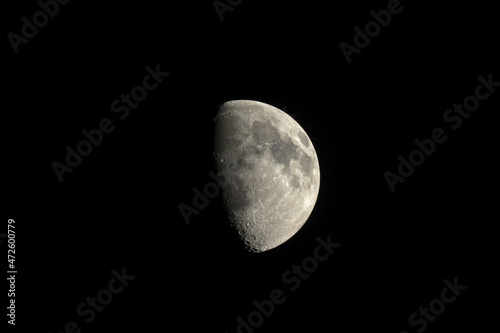 Color photograph of the growing moon at night against the black sky. Satellite of the Earth through a telescope. Craters and seas.