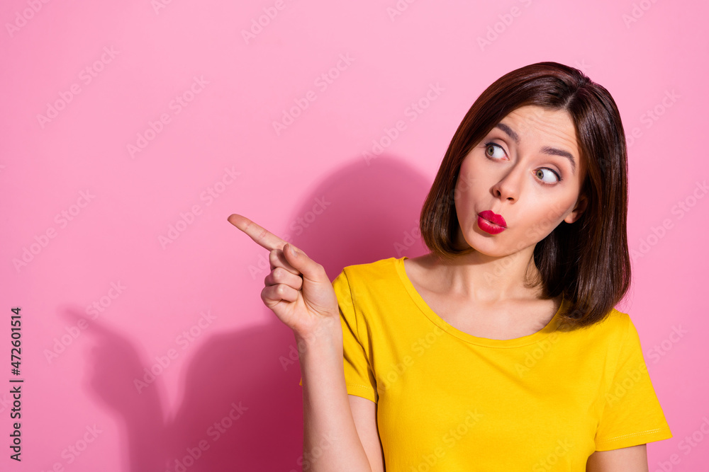 Photo of charming funny young woman wear yellow outfit lips pouted pointing empty space isolated pink color background Photo of charming funny young woman wear yellow outfit lips pouted pointing empty space isolated pink color background