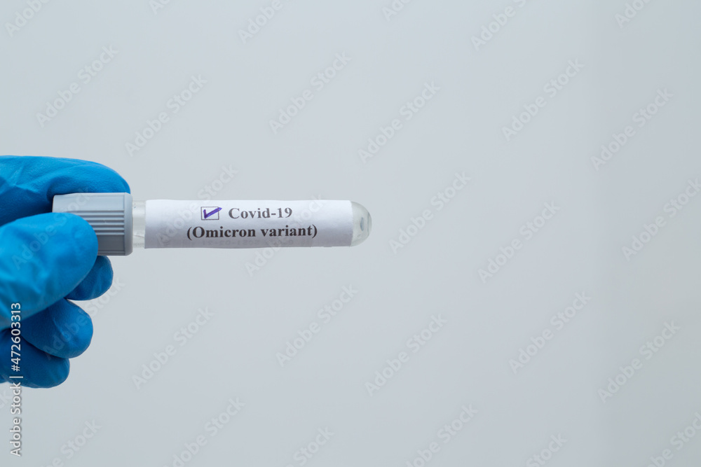 Fototapeta premium Hand holding tube which has text writen as Covid - 19 (Omicron vaiant) on with isolated white background. 