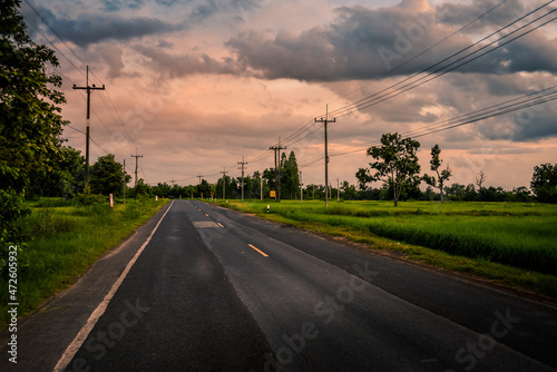 Fototapeta Naklejka Na Ścianę i Meble -  Rural roads with fields and skies background.Country Road.Paddy rice field green grass on beautiful blue sky background and road , home or village