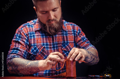 Craftsman produces leather workpiece at the workplace photo
