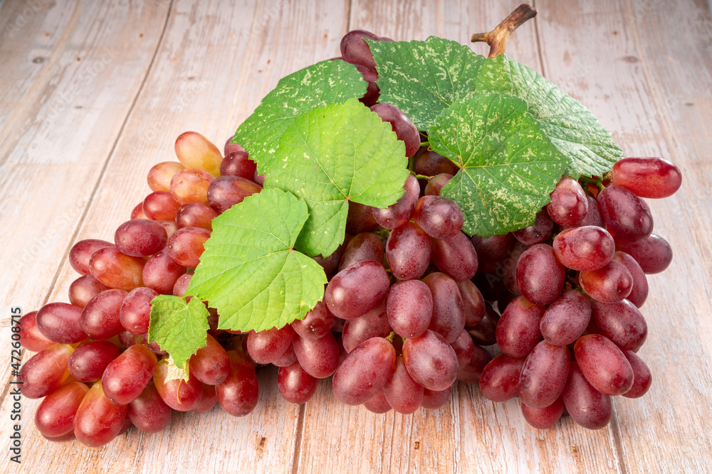 Red grape with leaves on wooden background, Bunch of fresh red grapes with leaves. Red grape with leaves on wooden background, Bunch of fresh red grapes with leaves.