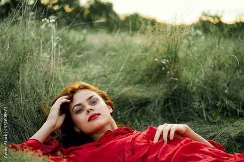 pretty woman in red dress lies on the grass freedom landscape © VICHIZH