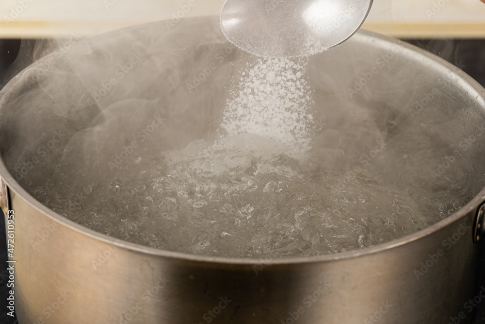 pour salt into a metal pot with boiling water with a spoon