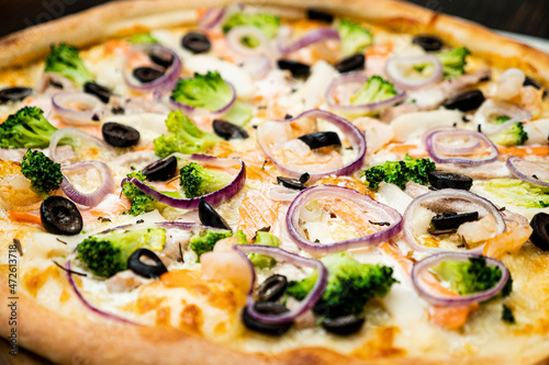 Pizza with seafood, olives, broccoli and onions