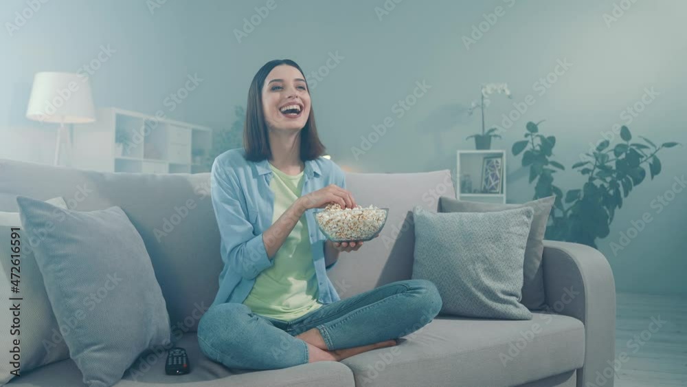 Excited lady sit divan look series laughter eat pop corn bowl in room Excited lady sit divan look series laughter eat pop corn bowl in room