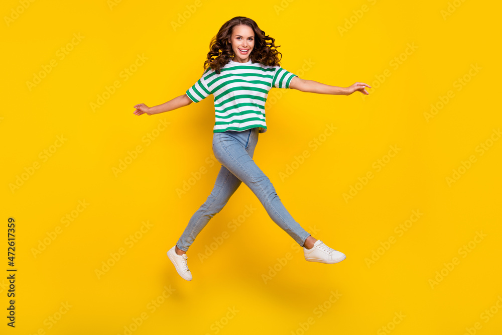 Full length photo of impressed brunette young lady wear t-shirt jeans footwear isolated on yellow background